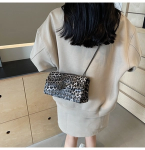 Gros plan d'un sac bandoulière léopard avec des clous métalliques et fine chaîne