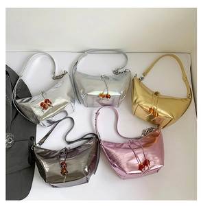 Detalle de bolsos con patrón de cocodrilo metalizado con cadenas de plata y cuentas ámbar