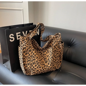 Dettaglio della borsa tote in tela leopardata con pratiche tasche laterali su divano