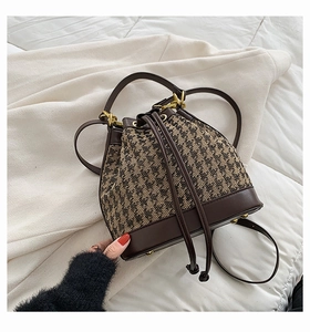 Detail of checkered bucket bag with leather drawstring closure and gold metal hardware