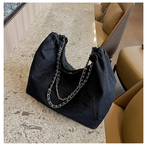Detail of black denim tote bag featuring dual silver chains and drawstring closure