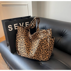 Dettaglio della borsa shopper leopardata con tasche laterali su divano in pelle