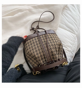 Detail of drawstring bucket bag in brown houndstooth fabric with gold hardware