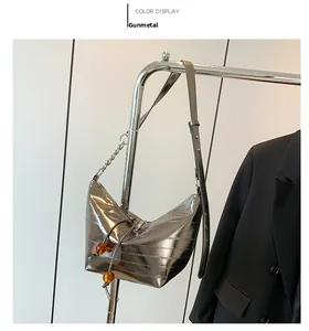 Detalle de bolso de hombro gunmetal texturizado con cadena plateada y cuentas ámbar