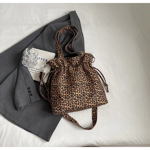 Detail shot of leopard print drawstring bucket bag on grey blazer with fashion accessories