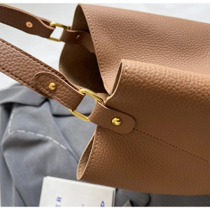 Gros plan détaillé du sac en cuir marron avec anneau doré et coutures précises