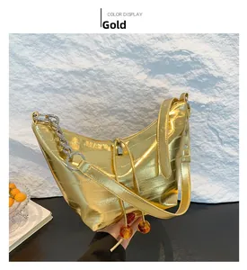 Detalle de bolso medialuna dorado con textura de cocodrilo y correa de cadena plata