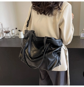 Rear view of a model in a cafe carrying a large black retro PU leather tote bag