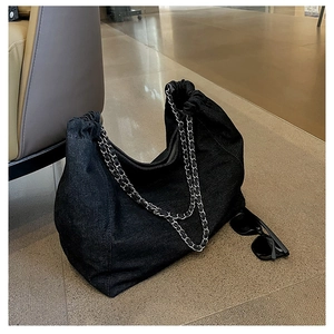 Detail of large black denim hobo bag with thick silver metal chain strap and pleats