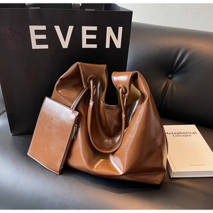 Detail of a brown slouchy tote bag and matching pouch on a black leather background