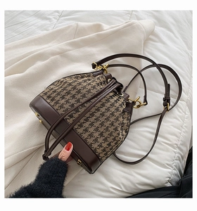 Detail of houndstock fabric bucket bag with drawstring closure and golden rivets