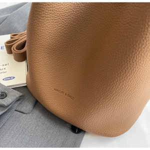 Détail du sac seau en cuir grainé marron avec coutures précises et logo gaufré