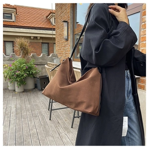 Détail du sac à bandoulière en daim marron avec finition mate et sangle en cuir noir