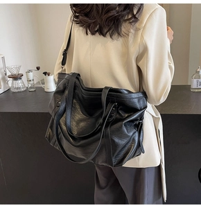 Detail of black PU leather tote bag with metal star stud and adjustable strap in a cafe