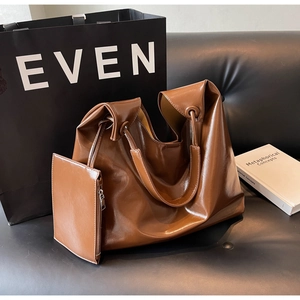 Detailed close-up of brown glossy PU leather tote bag with small matching zipper pouch