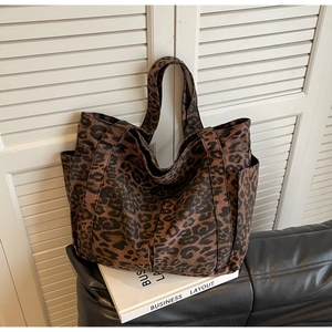 Dettaglio della borsa tote in tela leopardata con tasche laterali su un libro scenico