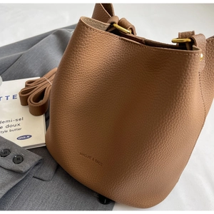 Détail du sac seau en cuir marron caramel montrant le grain de litchi et le fermoir doré