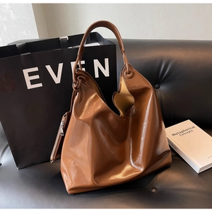 Detail view of brown large capacity tote bag with glossy texture and mini zip pouch on side