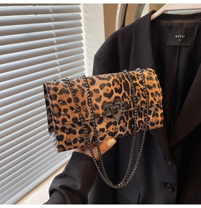 Détail d'un sac bandoulière léopard avec rivets métalliques et chaîne foncée