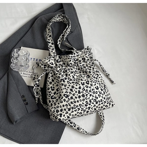 Close-up of leopard print canvas bucket bag featuring drawstring closure and outer pocket