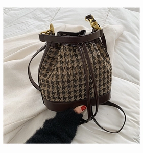 Detail of retro houndstooth fabric texture and premium leather drawstring of the bucket bag