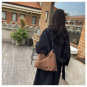 Grand sac cabas en daim marron au style rétro minimaliste porté par un mannequin