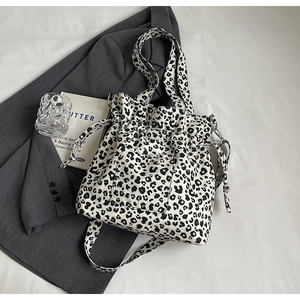Detail of drawstring closure and leopard print pocket on large canvas tote bag