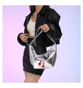 Detalle de bolso plateado metalizado con cordón ajustable y cuentas de ámbar