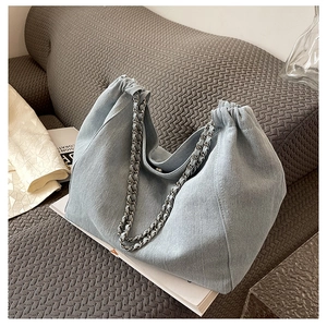 Detail of light blue denim tote bag featuring cloud pleats and silver chain strap