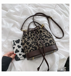 Detail view of leopard print bucket bag size compared with a smartphone on white fabric