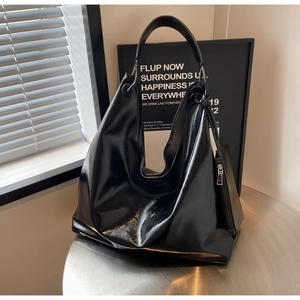Detail of glossy black large hobo bag on a metal table with a matching small zipper pouch