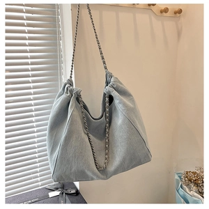Detail of light blue corduroy tote bag with silver chain strap hanging on a wall hook