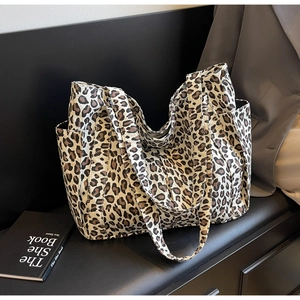 Dettaglio della borsa tote in tela leopardata con tasca laterale e manici rinforzati