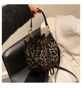 Detail of leopard print bucket bag featuring gold metal handles and drawstring closure