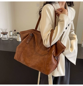 Detailed view of large brown retro tote bag with silver star studs and premium leather texture