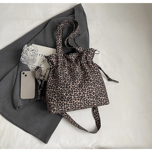 Detail view of leopard print canvas tote bag with drawstring closure on a grey blazer