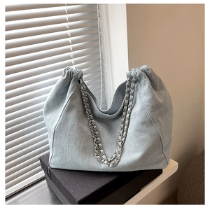 Detail of light blue denim hobo bag with silver metal chain strap and pleated design