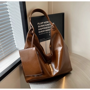 Detail of dark brown glossy leather tote bag showing spacious design and matching pouch