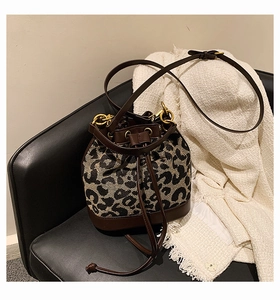 Detailed macro view of leopard print canvas texture and dark brown leather trim on bucket bag