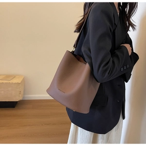 Détail d'un sac seau en cuir marron avec texture grainée et clous métalliques
