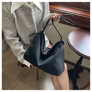 Détail d'un sac hobo noir montrant sa texture mate lisse et son beau drapé élégant