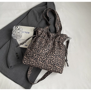 Leopard print canvas bucket bag featuring drawstring closure and adjustable strap on a grey blazer