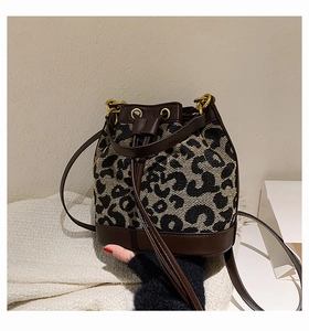 Close-up of leopard print bucket bag featuring drawstring closure and premium leather base