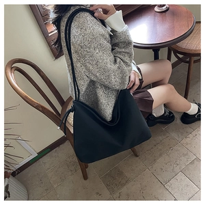 Détail d'un grand sac cabas noir en similicuir avec fines doubles anses et cordon de serrage