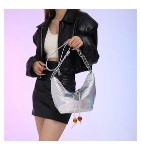 Detalle de bolso hobo plateado holográfico con cadena de metal y cordón con cuentas ámbar