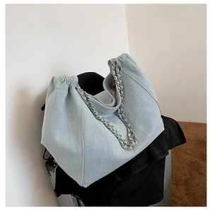Detail of light blue denim pleated tote bag featuring silver chain handle and soft fabric