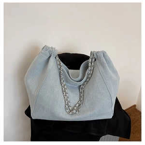 Detail of light blue denim tote bag with silver chain straps and gathered closure