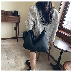 Détail du grand sac hobo noir mat porté par un mannequin dans un décor d'intérieur vintage