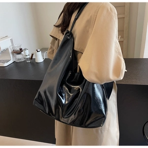Macro shot of large black glossy leather tote bag showing smooth shiny texture and folds