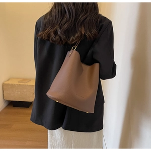 Sac seau en cuir marron avec pieds en métal et logo de la marque élégamment embossé